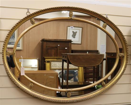 A gilt-framed oval wall mirror with marginal plates W.122cm